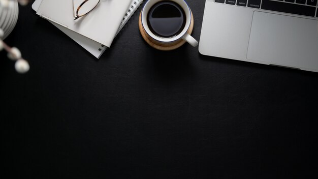 Photo aérienne d'un espace de travail avec un ordinateur portable, des cahiers, des lunettes, une tasse de café