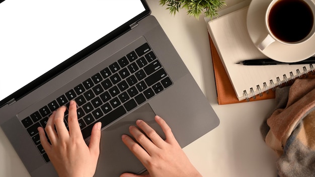 Photo aérienne d'une étudiante universitaire faisant ses devoirs avec un ordinateur portable à écran blanc sur le bureau