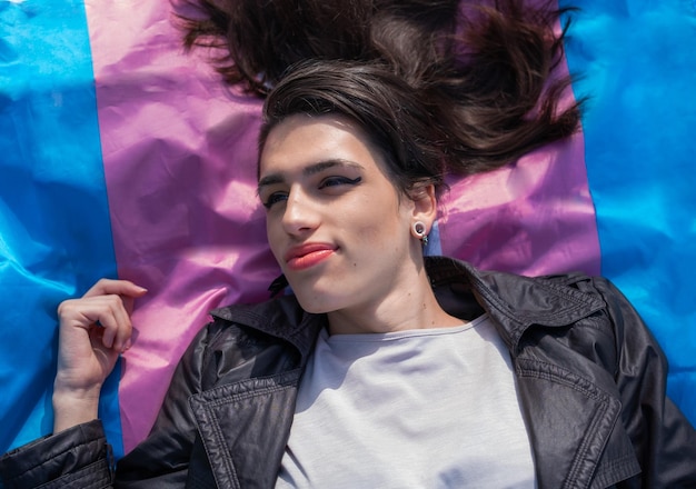 Photo aérienne d'une femme transsexuelle allongée sur le drapeau trans multicolore Nous activons LGTBIQ