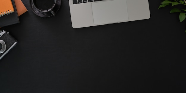 Photo aérienne d'un lieu de travail élégant et sombre avec un ordinateur portable et des fournitures de bureau sur tableau noir