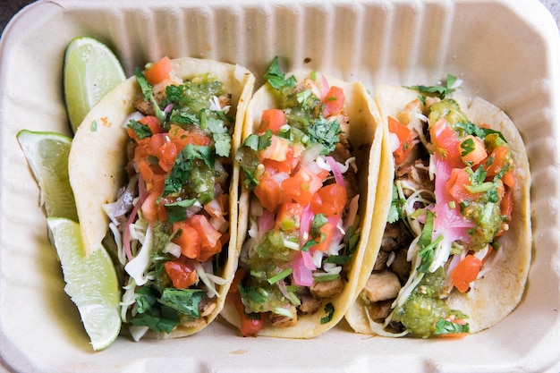 Photo aérienne de tacos de rue aux citrons verts dans une boîte à emporter