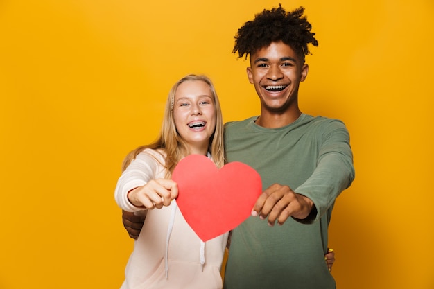 Photo d'amis adolescents homme et femme 16-18 holding paper heart, isolé sur fond jaune