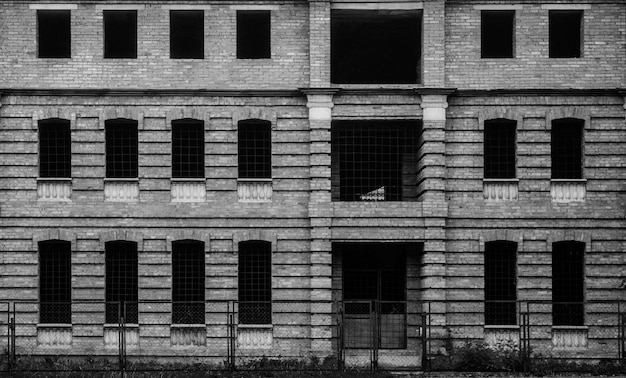 Photo de l'ancien bâtiment brun inachevé avec de nombreuses fenêtres en noir et blanc