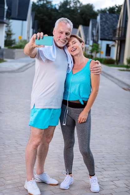 Photo après avoir couru. Couple moderne d'hommes d'affaires matures se sentant tout simplement incroyable en faisant un selfie après avoir couru ensemble