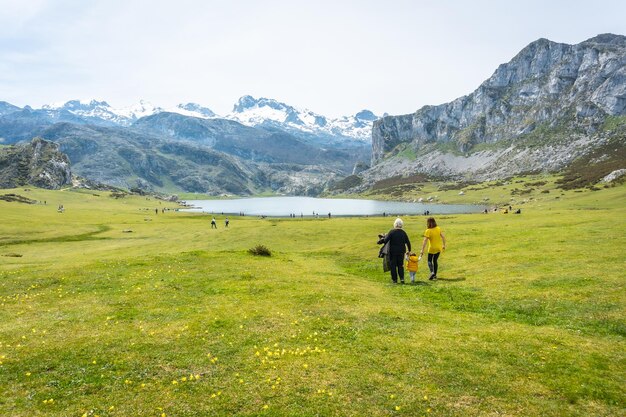 Photo une photo arrière de trois générations visitant le lac ercina par une journée ensoleillée dans les lacs de covadonga en espagne