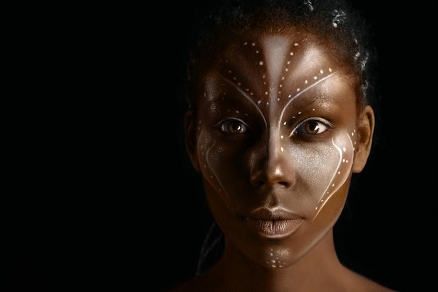 Photo d'art d'une femme africaine avec des peintures ethniques tribales sur son visage