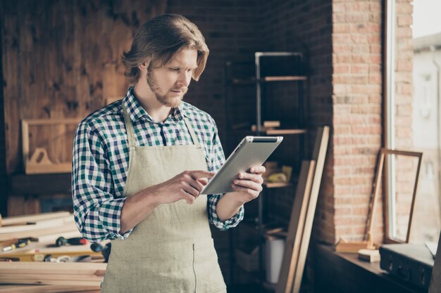 Photo d'artisan barbu posant dans sa menuiserie avec tablette