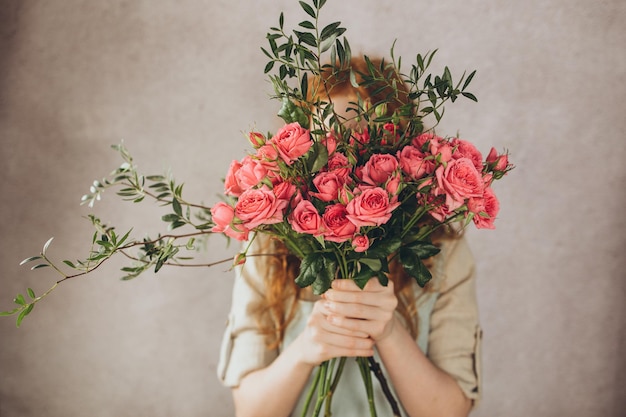 Photo atmosphérique d'une fille qui se couvre le visage d'un bouquet de roses roses
