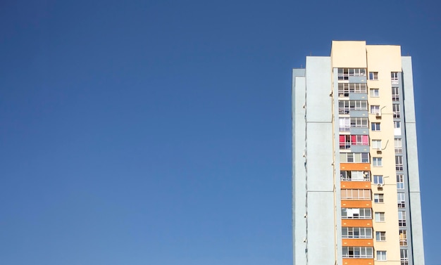 Photo d'un bâtiment à plusieurs étages contre le ciel bleu à droite avec un espace de copie à gauche