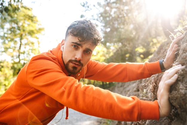 Photo de beau jeune coureur de fitness sports homme à l'extérieur dans le parc.