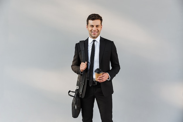 Photo de beau jeune homme d'affaires dans des vêtements formels à l'extérieur dans la rue tenant du café.