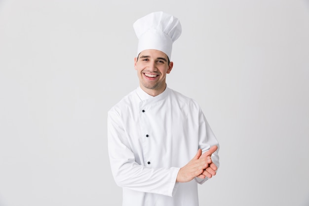 Photo de beau jeune homme chef à l'intérieur isolé sur fond de mur blanc posant.