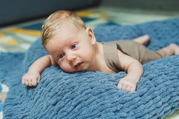 Photo d'un bébé dans une combinaison tricotée Un petit garçon nouveau-né est allongé sur une couverture tricotée grise Portrait d'un enfant d'un mois