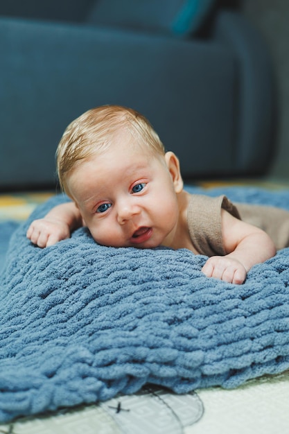 Photo d'un bébé dans une combinaison tricotée Un petit garçon nouveau-né est allongé sur une couverture tricotée grise Portrait d'un enfant d'un mois