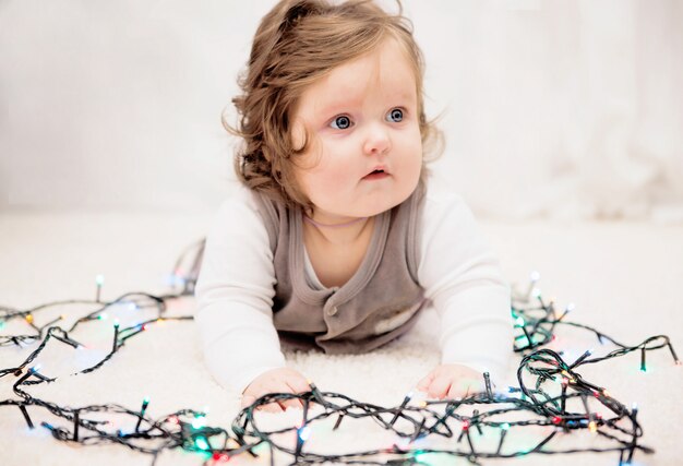 Photo de bébé dans les lumières du nouvel an sur le tapis