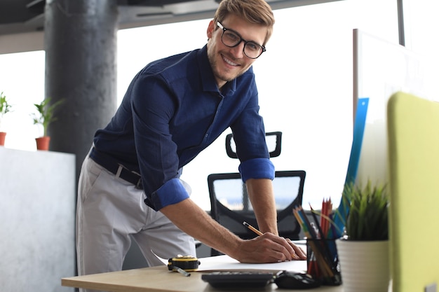 Photo d'un bel architecte masculin travaillant sur un dessin dans son bureau.