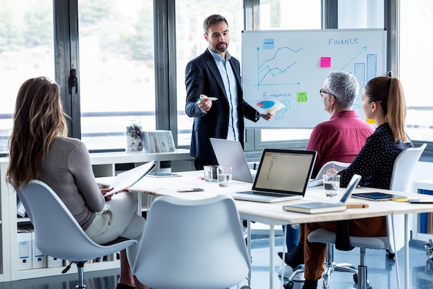 Photo d'un bel homme d'affaires expliquant un projet à ses collègues sur un lieu de coworking.