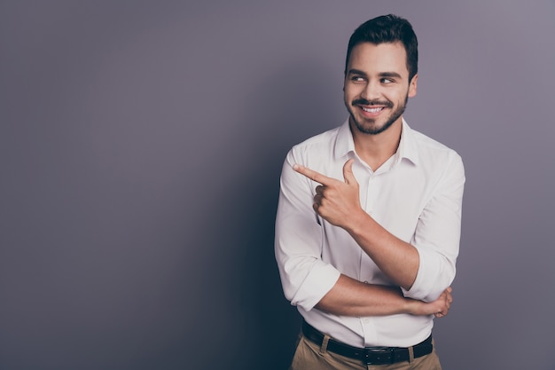 Photo de bel homme d'affaires sympathique souriant indiquant l'espace vide du doigt