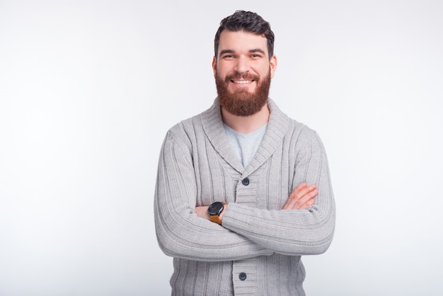 Photo de bel homme en pull debout sur fond blanc avec les bras croisés