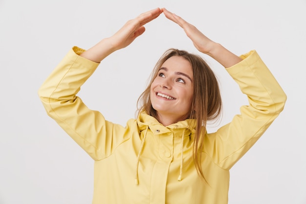 Photo d'une belle femme heureuse en imperméable faisant un geste de toit et souriant