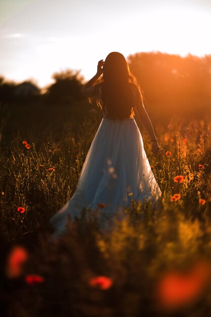 Photo d'une belle femme heureuse en robe élégante souriante dans un champ de blé