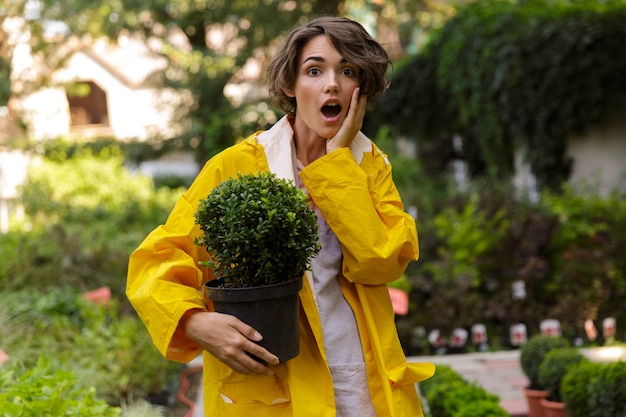 Photo de belle femme mignonne choquée jardinier debout sur les plantes à fleurs dans les plantes à effet de serre