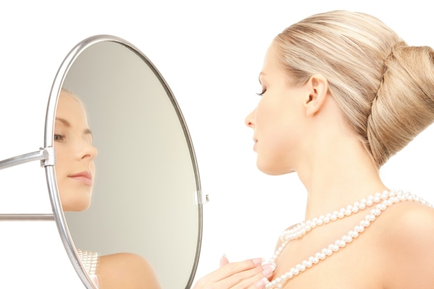 photo de belle femme avec des perles et un miroir.