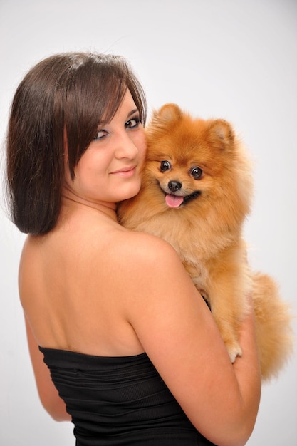 Photo d'une belle fille avec un chien entre les mains du studio de tournage en robe de soirée