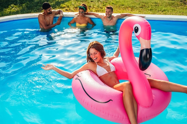 Photo d'une belle jeune brune sur un lilo avec ses amis en arrière-plan