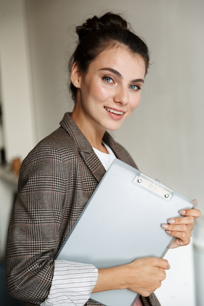 Photo d'une belle jeune femme d'affaires joyeuse à l'intérieur à la maison tenant un presse-papiers