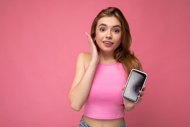 Photo d'une belle jeune femme blonde étonnée portant un haut rose en équilibre isolé sur fond rose