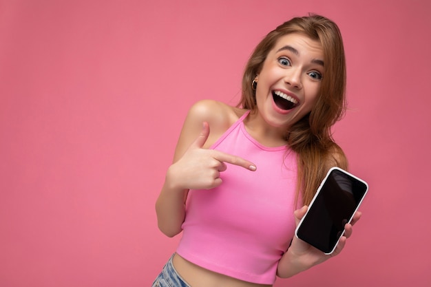 Photo d'une belle jeune femme blonde joyeuse et heureuse portant un haut rose en équilibre isolé sur rose