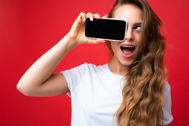 Photo de belle jeune femme blonde souriante beau portant un t-shirt blanc isolé sur permanent