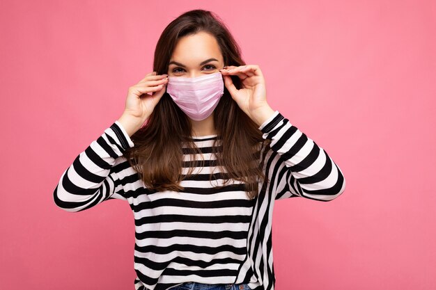 Photo d'une belle jeune femme brune dans un masque de protection anti-virus réutilisable sur le visage contre