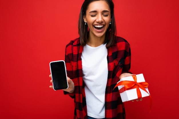 Photo d'une belle jeune femme brune riante positive isolée sur un mur de fond rouge portant