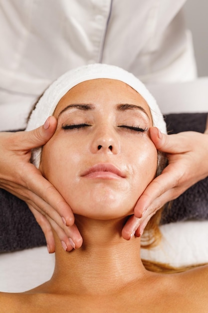 Photo d'une belle jeune femme profitant d'un massage du visage au salon de beauté.
