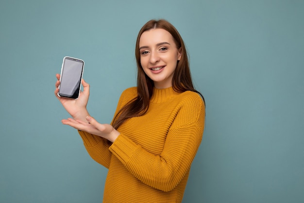 Photo de belle jeune femme souriante à la recherche de vêtements élégants décontractés debout isolé