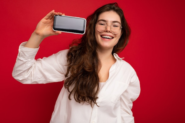 Photo de belle jeune femme souriante à la recherche de vêtements élégants décontractés debout isolé