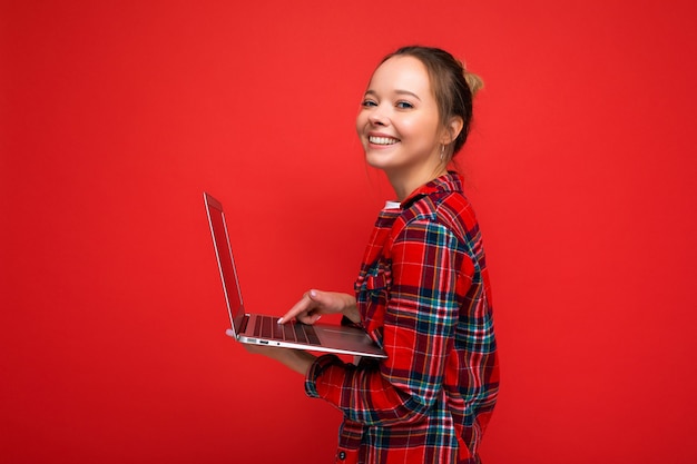 Photo de belle jeune fille tenant un ordinateur portable regardant la caméra isolée sur colorée