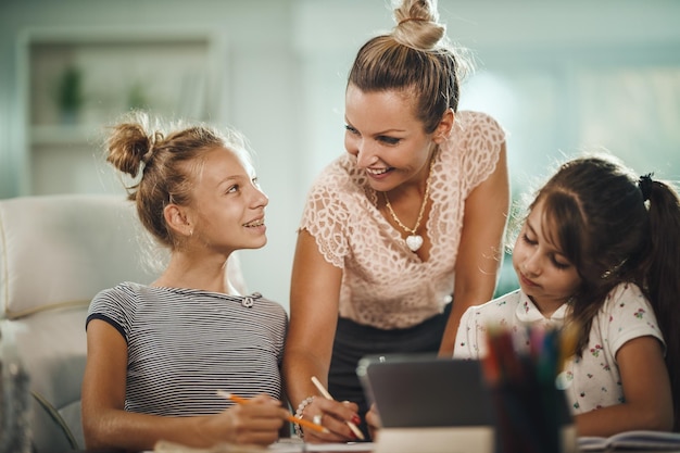 Photo d'une belle jeune mère aidant ses deux filles à faire leurs devoirs pendant la pandémie de COVID-19.