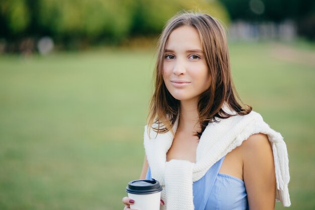 Photo de la belle petite amie avec un chandail blanc sur les épaules, des boissons à emporter du café