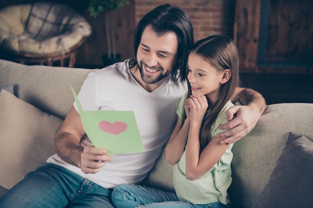 Photo de belle petite fille adorable et beau jeune papa assis sur un canapé confortable