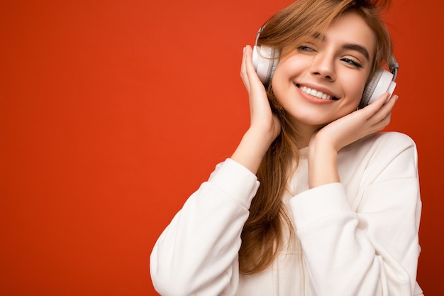 Photo de belle sexy heureuse souriante jeune femme blonde portant un sweat à capuche blanc isolé sur coloré