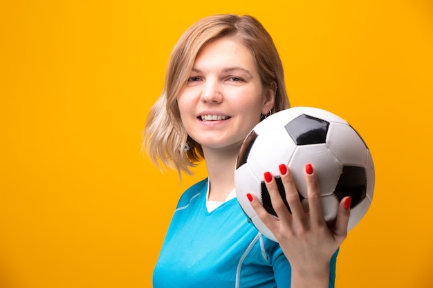 Photo de blonde avec ballon de football sur fond jaune en studio