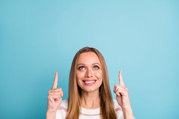 Photo de bonne humeur positive jolie jolie femme sourire à pleines dents pointant vers le haut aux ventes a commencé mur de couleur bleu pastel isolé