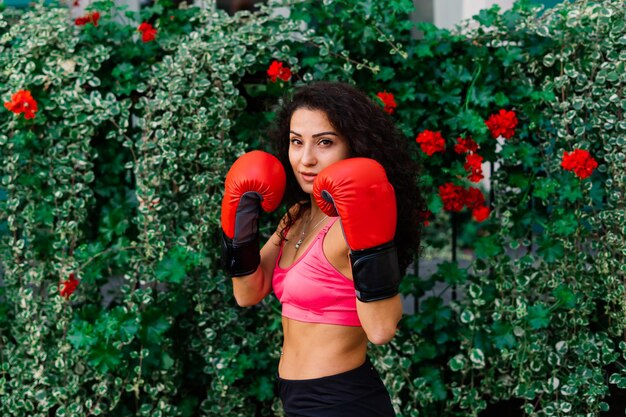 Photo d'un boxeur femme fitness fort en gants posant à l'extérieur.