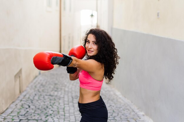 Photo d'un boxeur femme fitness fort en gants posant à l'extérieur.