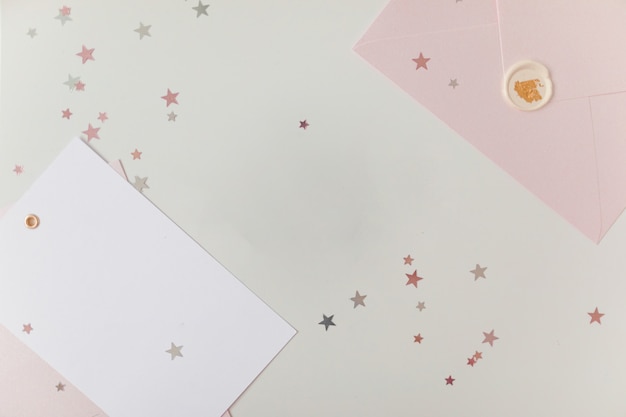 Photo de carte blanche vierge dans une enveloppe rose fond de couleur woodden isolé avec des étoiles scintillantes, vaucher, certificat-cadeau. Fond blanc et rose
