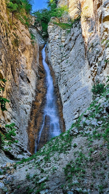 Photo sur la photo, une cascade qui tombe d'une haute falaise dans les montagnes du caucase.