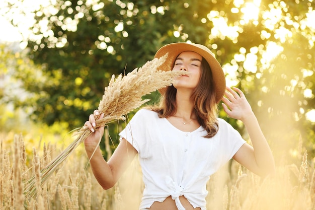 Photo d'une charmante femme caucasienne au chapeau de paille reposant sur un champ de blé le jour d'été